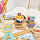Handmade felt ornament of a young girl reading with a stack of books, super star badge and a tote of books ornaments around her. Crafted from natural merino-blended wool, her focused gaze and relaxed posture capture the magic of reading. With braided brown hair and a warm-toned complexion, this ornament adds a cozy, literary touch to reading nooks, desks, or shelves. A perfect gift for bookworms, young readers, or anyone who treasures the quiet joy of a good story. Ready to hang with a string attached