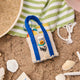 Handmade felt Beach Bag ornament from Craftspring, displayed on a sandy shore with seashells—heirloom-quality summer decor that brings sunny, coastal vibes to your celebrations, ethically crafted by artisans in India using sustainable wool.