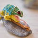 Craftspring’s handmade felt Chameleon Christmas ornament displayed on a rock—featuring beaded details, a curled tail, and a long tongue catching a bug, perfect for fun and unique holiday gifting, ethically crafted by artisans using sustainable wool.