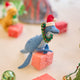 Handmade felt Santa Plesiosaurus ornament from Craftspring, featuring a dinosaur with a Santa hat, festive wreath, and beaded and embroidered details—displayed with a mini present, perfect for dino-loving kids and whimsical Christmas gifting, ethically crafted by artisans using sustainable wool.