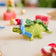 Handmade felt Santa Stegosaurus ornament from Craftspring, featuring a green dinosaur with embroidered spots and a festive red Santa hat—whimsical holiday decor with a prehistoric twist, ethically crafted by artisans using sustainable wool.