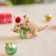 Handmade felt Santa Triceratops ornament from Craftspring, displayed on marble with mini wrapped presents and bobble ornaments—perfect for dino-loving kids and joyful holiday gifting, bringing warm festive cheer, ethically crafted by artisans using sustainable wool.