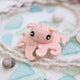 Handmade felt Dumbo Octopus ornament from Craftspring, featuring adorable curly pink tentacles and charming embroidered details—cuddled among sea glass, rope, and shells for a sweet coastal Christmas vibe, lovingly crafted by artisans using sustainable wool.