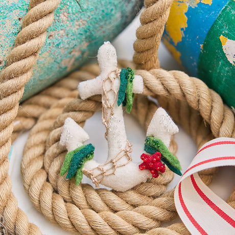 Handmade felt Anchor ornament from Craftspring, featuring beaded barnacles, appliqué seaweed and starfish, and draped in netting—displayed with rope and lobster buoys, perfect for nautical holiday decor and gifting, sustainably handmade by artisans using wool.
