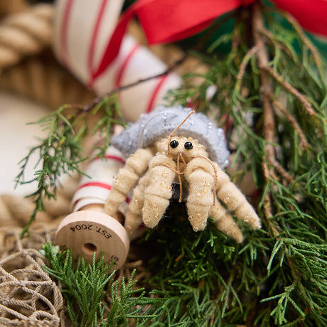 Handmade felt Hermit Crab Christmas ornament from Craftspring, with intricate beaded and embroidered details—displayed among evergreens, perfect for ocean lovers and whimsical holiday gifting, sustainably handmade by artisans.
