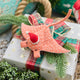 Handmade felt Santa Coral Manta ornament from Craftspring, featuring intricate beaded and embroidered details and a festive Santa hat—displayed on a Christmas gift for a whimsical coastal holiday scene, ethically crafted by artisans using sustainable wool.