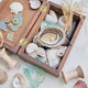 Lifestyle photo of Craftspring’s handmade felt Oyster Christmas ornament, nestled in a wooden box filled with shells and sea glass—featuring a beaded pearl and shimmering embroidered details, ethically crafted by artisans using sustainable wool for ocean-inspired holiday charm.










