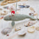 Craftspring’s handmade felt Santa Spyhop Gray Whale Christmas ornament displayed among seashells—featuring intricate embroidered details and a festive red Santa hat, perfect for coastal holiday gifting, ethically crafted by artisans using sustainable wool.