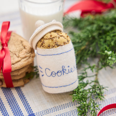Handmade felt Cookie Jar ornament from Craftspring, featuring a classic cookie jar filled with chocolate chip cookies and detailed with embroidery and beads—displayed with evergreen branches, milk, and cookies, perfect for cozy Christmas decorating and festive gifting, ethically crafted by artisans using sustainable wool.