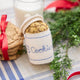 Handmade felt Cookie Jar ornament from Craftspring, featuring a classic cookie jar filled with chocolate chip cookies and detailed with embroidery and beads—displayed with evergreen branches, milk, and cookies, perfect for cozy Christmas decorating and festive gifting, ethically crafted by artisans using sustainable wool.