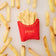 Lifestyle photo of Craftspring’s French Fries ornament, featuring golden felt fries with playful embroidered details—displayed on a marble surface surrounded by real French fries, perfect for food lovers and whimsical holiday gifting, ethically handmade by artisans using sustainable wool.