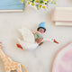 Handmade felt Cloud Dancer Dream Goose ornament – Brown – from Craftspring, displayed on marble with a baby hat, toys, and ribbons—featuring a baby with brown skin and black hair riding a white goose, perfect as a charming nursery decoration and thoughtful keepsake, ethically crafted by artisans using sustainable wool.