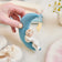 Handmade felt Moon Dreamer Baby Ornament – Light from Craftspring, held in hand and surrounded by baby booties, a baby hat, and flowers—featuring a sleeping baby with light skin on a crescent moon with a dangling star, perfect for nursery decor and heartfelt baby shower gifting, ethically crafted using sustainable wool.