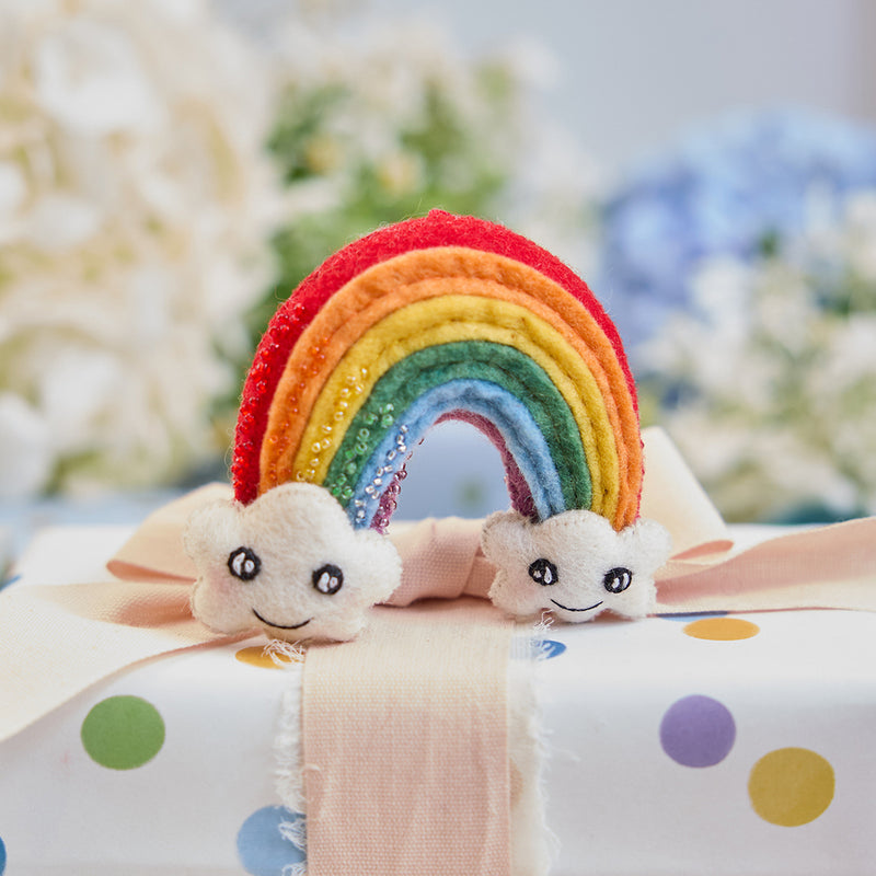 Handmade felt Cute You & Me Rainbow ornament from Craftspring, featuring intricate beaded and embroidered details with cute faces on clouds—displayed on a wrapped gift, perfect for nursery decor and thoughtful baby shower gifting, ethically crafted by artisans using sustainable wool.