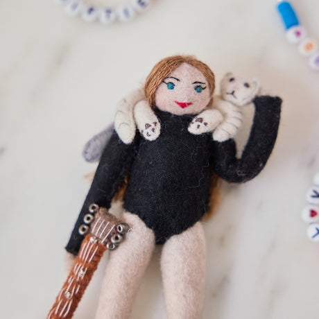 Craftspring’s handmade felt Taylor Swift with Cat Christmas ornament displayed surrounded by friendship bracelets—featuring Taylor holding a guitar with the number 13 and a cat around her shoulders, perfect for Swiftie holiday gifting, ethically crafted by artisans using sustainable wool.