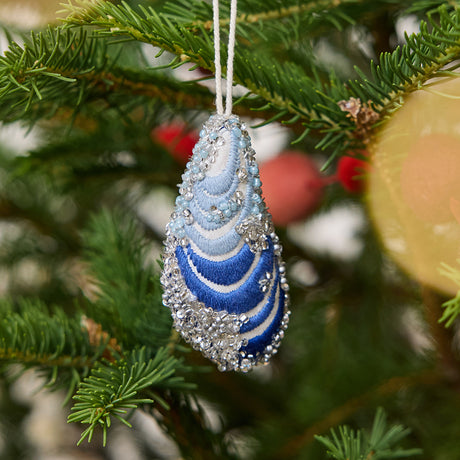 Craftspring’s Mussel Shell Ornament displayed on a Christmas tree — made of satin with intricate beaded and embroidered details, adding Maine-themed holiday charm and festive gifting warmth, ethically crafted by artisans.