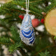 Craftspring’s Mussel Shell Ornament displayed on a Christmas tree — made of satin with intricate beaded and embroidered details, adding Maine-themed holiday charm and festive gifting warmth, ethically crafted by artisans.