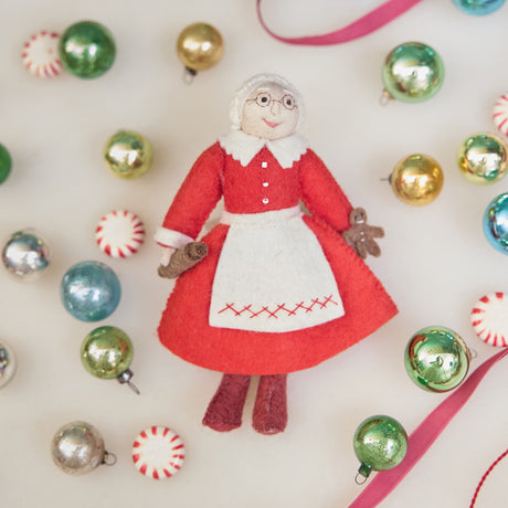 Felt Mrs. Clause ornament in a red dress surrounded by colorful Christmas ornaments. Holiday Joy filled with sugar and spice
