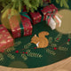 Craftspring’s Woodland Tree Skirt displayed under a Christmas tree with presents — close-up of the embroidered and appliqué squirrel nestled among pine branches and red berries, highlighting festive holiday details, ethically crafted by artisans using sustainable wool.