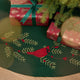 Craftspring’s Woodland Tree Skirt displayed under a Christmas tree with presents — close-up of the embroidered and appliqué cardinal nestled among pine branches and red berries, highlighting festive holiday details, ethically crafted by artisans using sustainable wool.