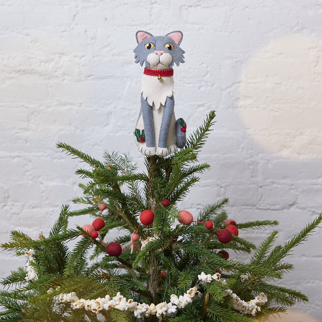 Handmade felt Gray Cat Tree Topper from Craftspring, featuring holly accents and a red collar with a bell—displayed on top of a Christmas tree, perfect for festive feline lovers, whimsical holiday decorating, and thoughtful Christmas gifting, ethically crafted by artisans using sustainable wool.