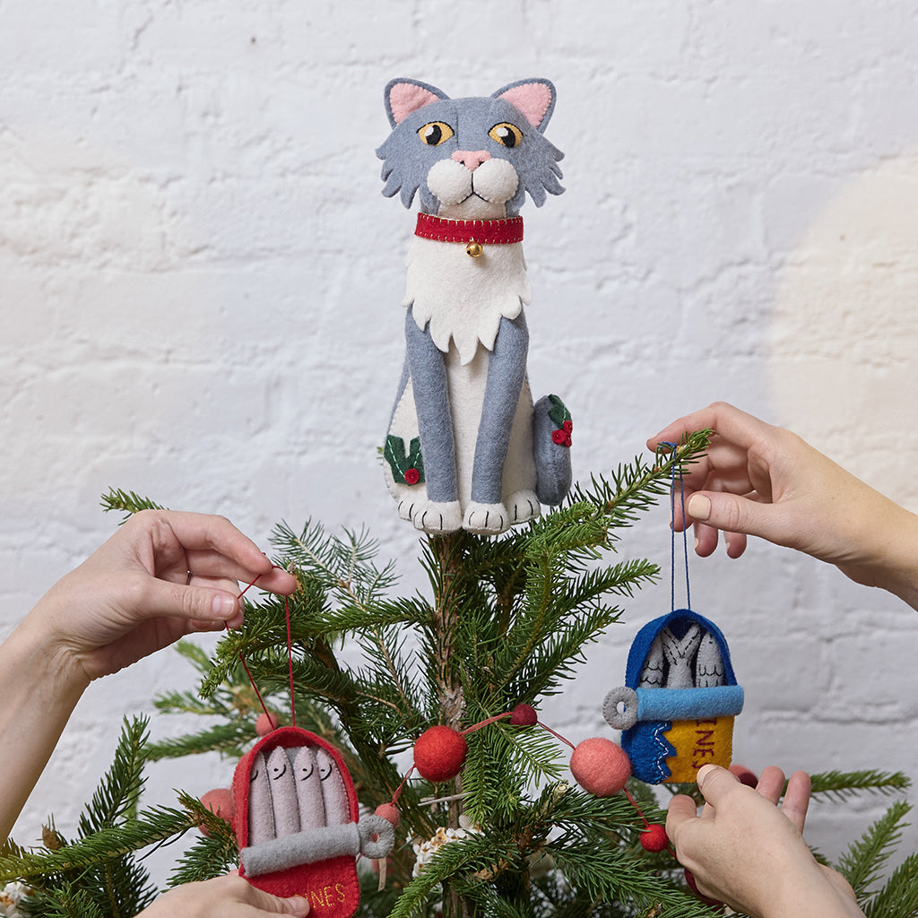 Handmade felt Gray Cat Tree Topper from Craftspring, featuring holly accents and a red collar with a bell—displayed on a Christmas tree decorated with sardine ornaments, perfect for cat lovers and playful holiday decorating, ethically crafted by artisans using sustainable wool.