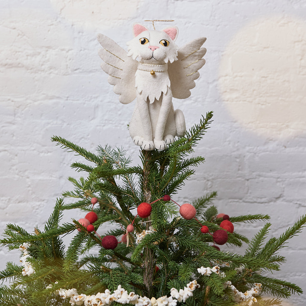 Handmade felt Angel Cat Tree Topper from Craftspring, featuring white angel wings, a halo, a white collar with a bell, and gold embroidered details—displayed on a Christmas tree, perfect for whimsical holiday decorating and thoughtful gifting, ethically crafted by artisans using sustainable wool.