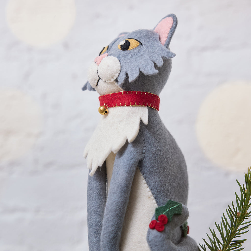 Handmade felt Gray Cat Tree Topper from Craftspring, featuring holly accents and a red collar with a bell—displayed on top of a Christmas tree, perfect for festive feline lovers, whimsical holiday decorating, and thoughtful Christmas gifting, ethically crafted by artisans using sustainable wool.