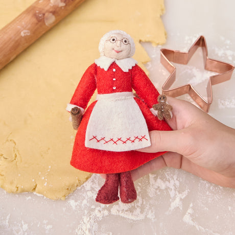 Capture a moment of sweet holiday joy, holding a Mrs. Clause ornament while baking gingerbread.