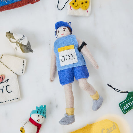 Craftspring’s handmade felt Marathon Runner ornament — featuring a runner with a race bib numbered 001 and an armband, displayed among other NYC-themed ornaments for a festive holiday scene, perfect for Christmas decorating or gifting, ethically crafted by artisans using sustainable wool.