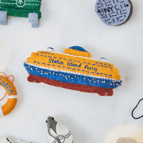Craftspring’s handmade felt Staten Island Ferry ornament — featuring intricate embroidered details and beaded waves on the iconic orange ferry, displayed surrounded by the NYC Mini Ornaments Set of 24 for a festive holiday scene, perfect for Christmas decorating or gifting, ethically crafted by artisans using sustainable wool.