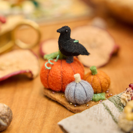 This is what I would prefer: Craftspring’s handmade felt Pumpkin Patch ornament — featuring pumpkins and a crow, with beaded and embroidered details, displayed on a harvest table among dried apple slices and mini pumpkins for a cozy autumn scene, perfect for Halloween, Thanksgiving, and holiday gifting, ethically crafted by artisans using sustainable wool.