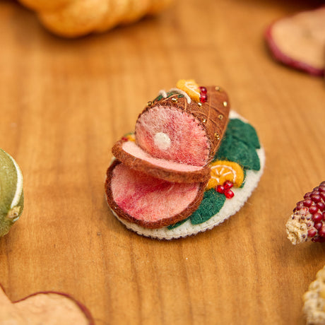 Craftspring’s handmade felt Spiral Ham Platter ornament — a festive ham with intricate beaded and embroidered details, displayed on a harvest table with dried apple slices and pumpkins for a warm holiday scene, perfect for Thanksgiving decorating or gifting, ethically crafted by artisans using sustainable wool.