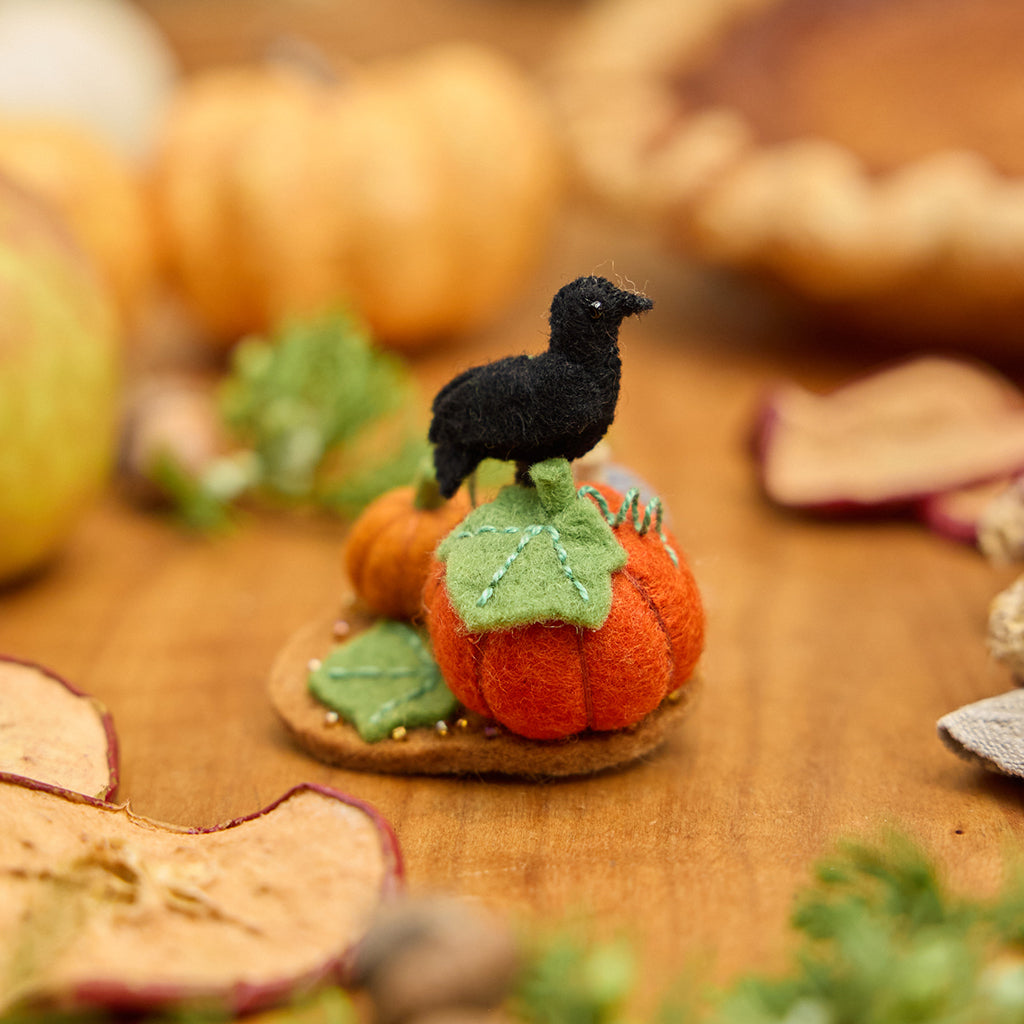 This is what I would prefer: Craftspring’s handmade felt Pumpkin Patch ornament — featuring pumpkins and a crow, with beaded and embroidered details, displayed on a harvest table among dried apple slices and mini pumpkins for a cozy autumn scene, perfect for Halloween, Thanksgiving, and holiday gifting, ethically crafted by artisans using sustainable wool.
