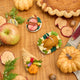 Craftspring’s handmade felt Cornucopia, Turkey Dinner, and Spiral Ham ornaments — a crocheted raffia cornucopia filled with felt and beaded vegetables and fruit, a roasted turkey with autumn sides, and a spiral ham, displayed on a harvest table with pie, apples, and pumpkins for a cozy holiday scene, perfect for Thanksgiving decorating or gifting, ethically crafted by artisans using sustainable wool.