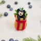Craftspring’s handmade felt Adirondack Basket with Black Bear Cub ornament — a cozy brown basket with a playful black bear cub peeking out, displayed with evergreens and blueberries for a rustic holiday touch, perfect for Christmas decorating or gifting, ethically crafted by artisans using sustainable wool.