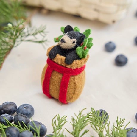Craftspring’s handmade felt Adirondack Basket with Black Bear Cub ornament — a cozy brown basket with a playful black bear cub peeking out, displayed with evergreens and blueberries for a rustic holiday touch, perfect for Christmas decorating or gifting, ethically crafted by artisans using sustainable wool.