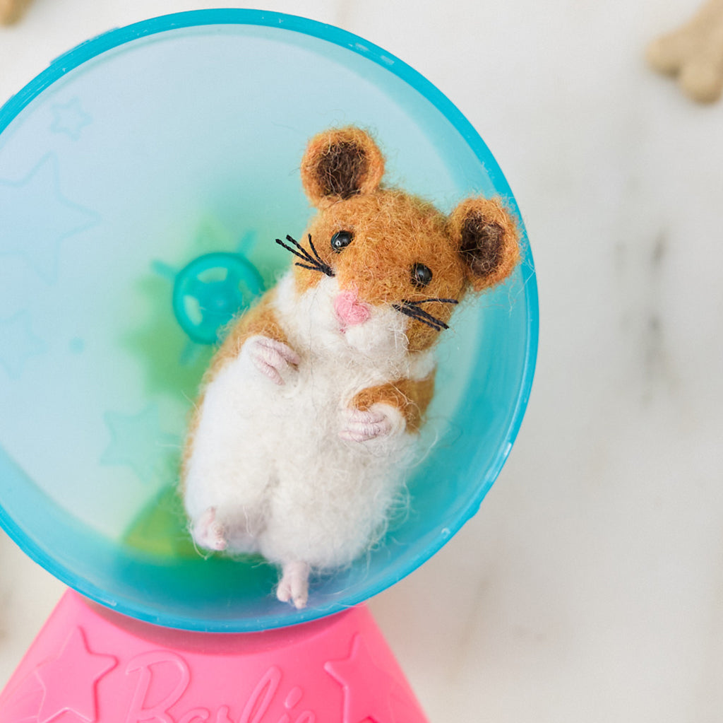 Craftspring’s handmade felt Hamster ornament displayed in a miniature hamster wheel—needle-felted with tiny whiskers and paws, bringing playful holiday charm and gifting warmth, ethically crafted by artisans using sustainable wool.