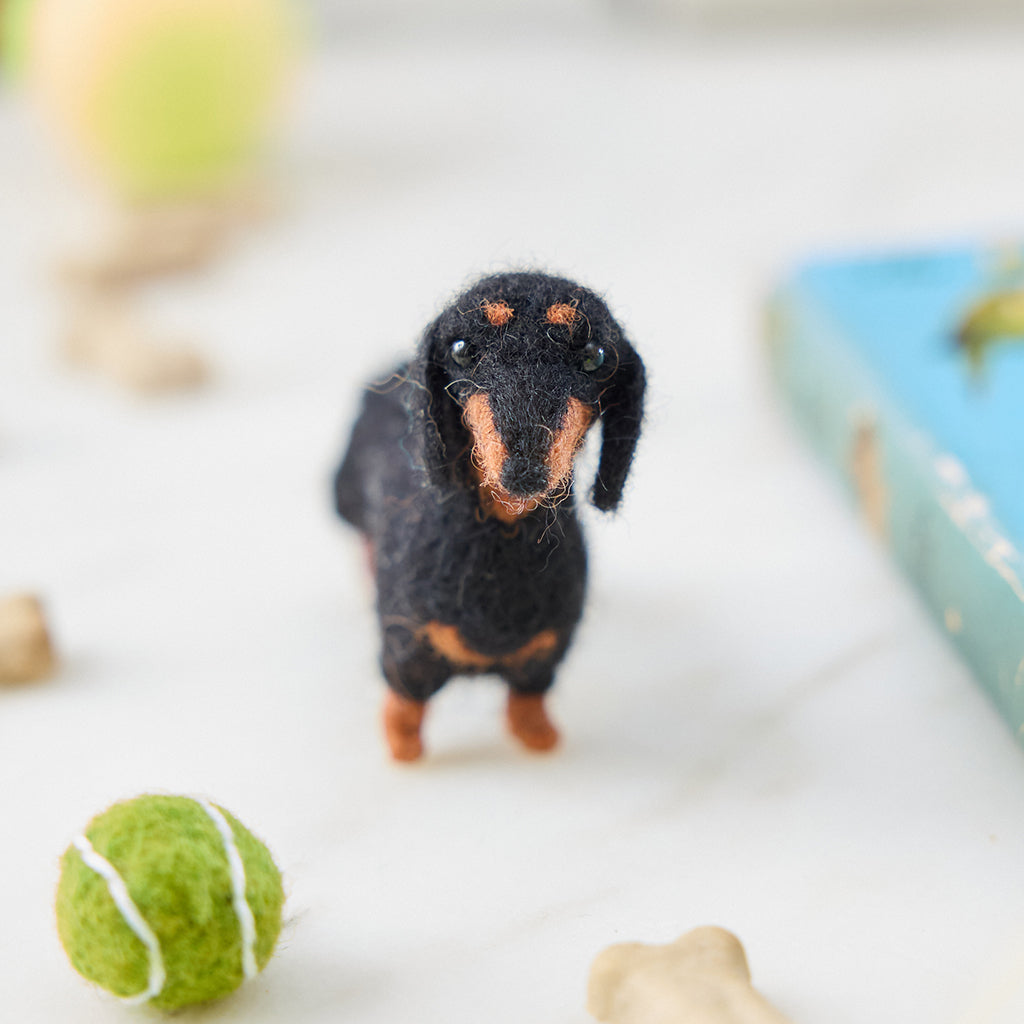 Craftspring’s needle-felted Dachshund Ornament with short legs and a cute face, displayed among dog treats and toys — a playful and charming holiday decoration, perfect for gifting, ethically crafted by artisans using sustainable wool.