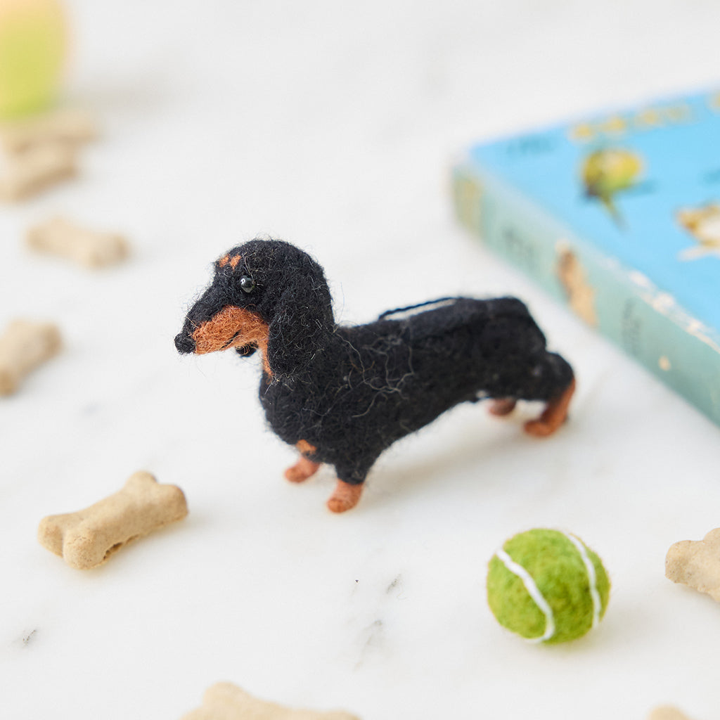 Craftspring’s needle-felted Dachshund Ornament with short legs and a cute face, displayed among dog treats and toys — a playful and charming holiday decoration, perfect for gifting, ethically crafted by artisans using sustainable wool.