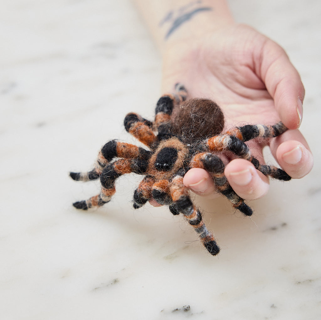 Craftspring’s needle-felted Tarantula Ornament with hairy legs, displayed crawling out of a hand as a playful and unusual pet — highlighting its charming needle-felted details and beaded eyes, perfect for gifting and holiday fun, ethically crafted by artisans using sustainable wool.