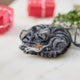 Craftspring’s needle-felted Sleepy Gray Cat Ornament displayed with evergreens and mini presents — with whiskers and a cute face, creating a cozy and festive holiday scene, perfect for gifting, ethically crafted by artisans using sustainable wool.