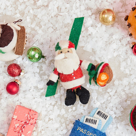 Craftspring’s handmade felt Italian Santa ornament — a cute Santa holding a panettone and wearing a helmet in Italian flag colors, displayed in snow with Christmas baubles for a festive holiday scene, perfect for Christmas decorating or gifting, ethically crafted by artisans using sustainable wool.