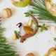 Craftspring’s Partridge in a Pear Tree Ornament — intricate beaded and embroidered partridge in a tree with dangling pears, displayed with golden walnuts and pine needles for a cozy holiday setting, ethically crafted by artisans using sustainable wool.