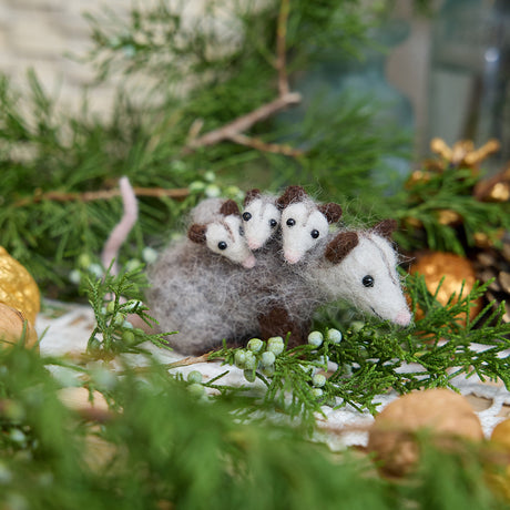 Craftspring’s Opossum Mom with Babies Ornament — needle felted with three babies on her back, cute faces and pink tails — displayed among evergreens, evoking the playful joy and cozy warmth of holiday gifting, ethically crafted by artisans using sustainable wool.