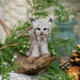 Craftspring’s Lynx ornament displayed standing on a stick among evergreens and pinecones — handmade from sustainable wool with intricate needle-felted details, whiskers, and ear tufts, ethically crafted by artisans for Christmas decorating and gifting.