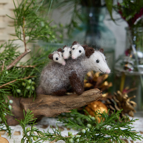 Craftspring’s Opossum Mom with Babies Ornament — handmade with three tiny babies with cute faces and pink tails — perched on a stick among evergreens, capturing whimsical holiday charm and heirloom-quality Christmas cheer, ethically crafted by artisans using sustainable wool.