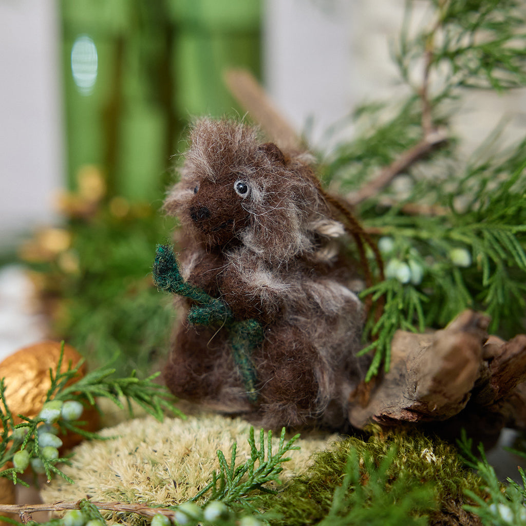 Craftspring’s Porcupine ornament nestled in a woodland-inspired holiday scene with moss, evergreens, and golden walnuts — handmade from sustainable wool with fuzzy quills and a leafy branch, ethically crafted by artisans for Christmas decorating and gifting.