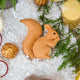 Craftspring’s handmade felt Red Squirrel ornament — featuring delicate beaded and embroidered details, displayed with evergreen branches and golden walnuts for a warm holiday scene, perfect for Christmas decorating or gifting, ethically crafted by artisans using sustainable wool.