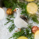 Craftspring’s Goose Ornament — needle felted with fluffy feathers and beaded eyes — displayed on snow with evergreens and golden walnuts, a festive holiday scene full of heirloom beauty, warmth, and Christmas gifting cheer, ethically crafted by artisans using sustainable wool.